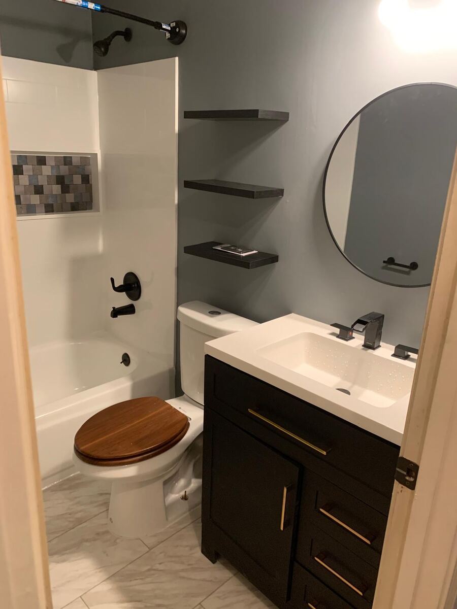 Finished bathroom with dark vanity and round mirror