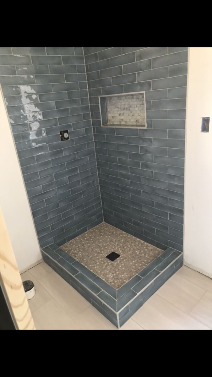 Blue subway tile shower with pebble floor