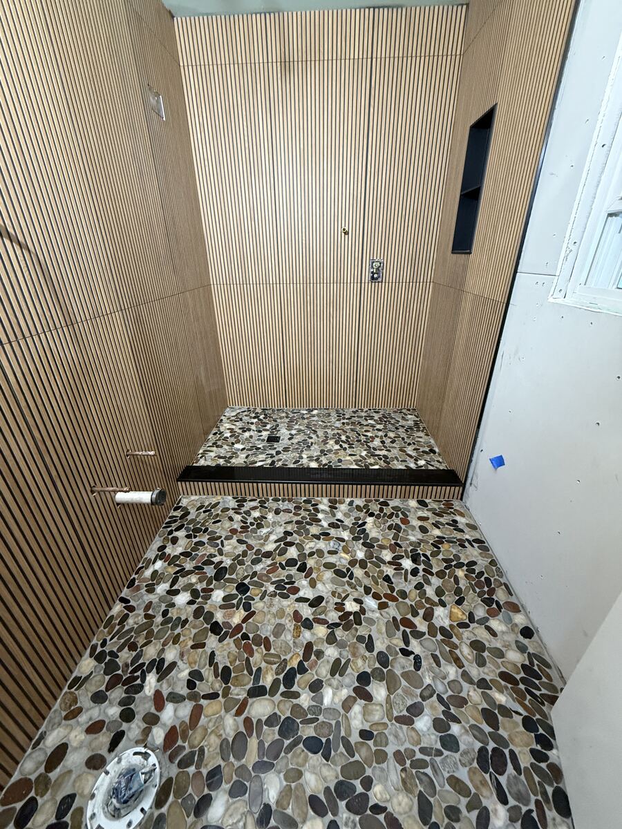 Wood-slat style shower wall with pebble floor