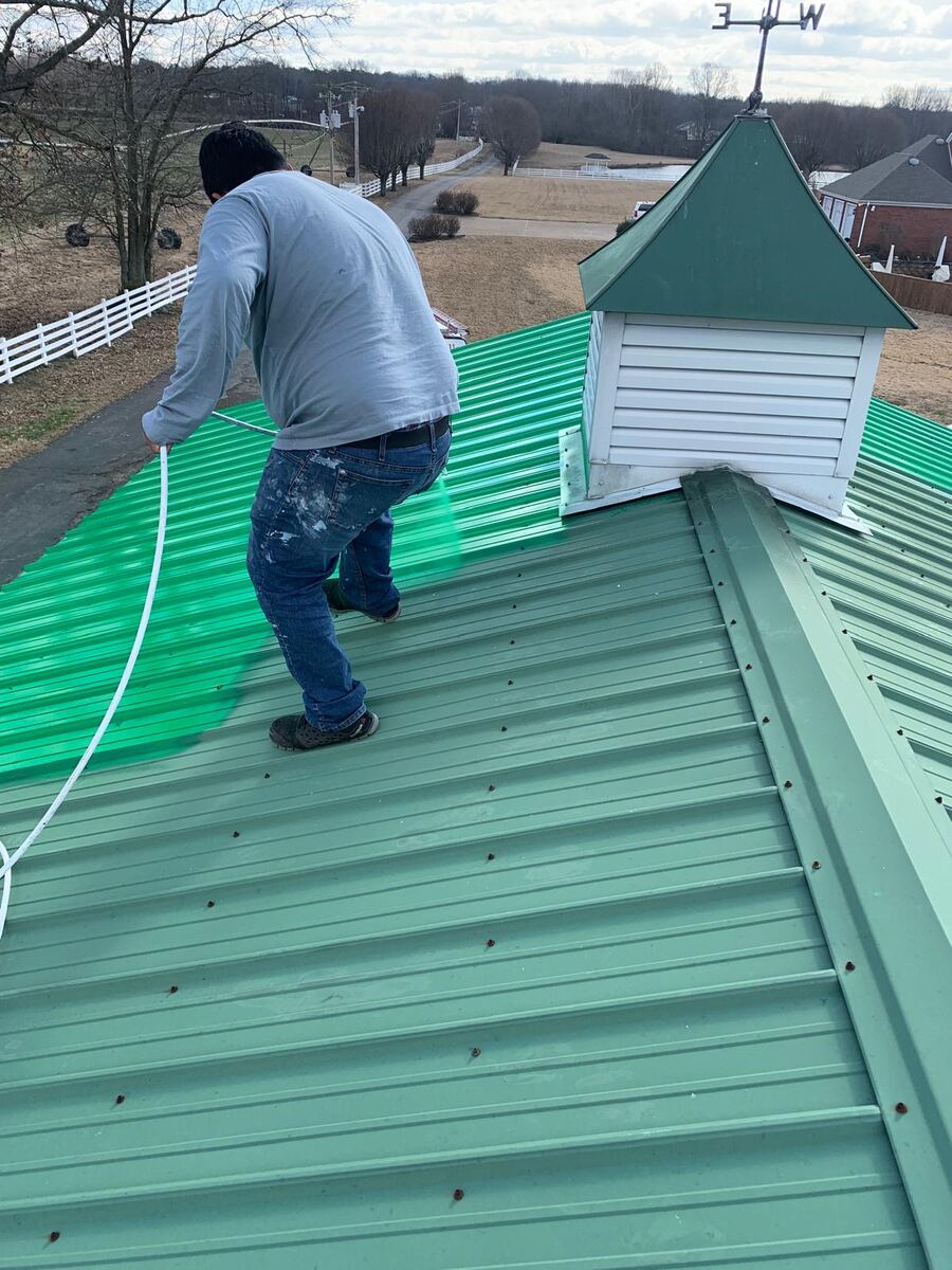 Metal barn roof being painted green